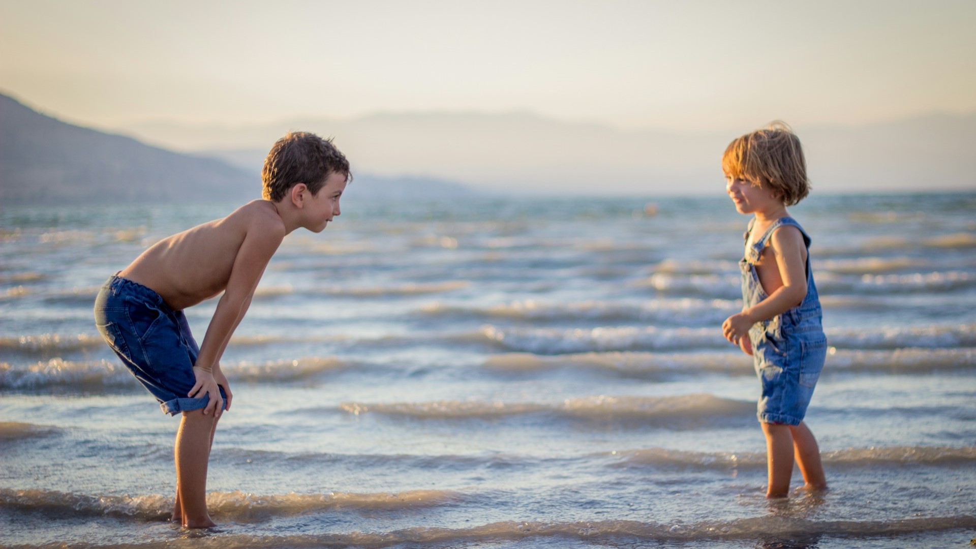 dvoje djece na plaži pored vode